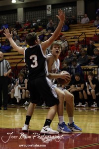 Otis-Bison Cougar Dylan Wissman (#11) makes a strong move towards the basket against Ellsworth Bearcat Shane Wilson (#3) at the 2012 Hoisington Winter Jam Basketball Tournament.
