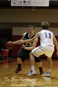 Ellsworth Bearcat Ben Murrell (#23) looks to drive past Otis-Bison Cougar Dylan Wissman (#11) at the 2012 Hoisington Winter Jam Basketball Tournament.