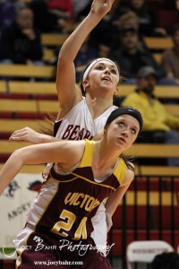 Connor Davis (#20) of the Ellsworth Lady Bearcats jumps up behind Rylee Broyles (#20) of the Victoria Lady Knights at the 2012 Hoisington Winter Jam Basketball Tournament.