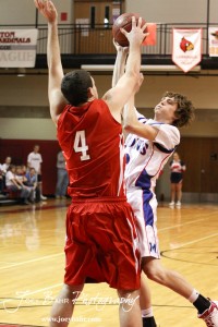 Cody Stetler (#4) of the Hoisington Cardinals blocks a shot taken by Josh Macy (#2) of the Minneapolis Lions at the 2012 Hoisington Winter Jam Basketball Tournament.