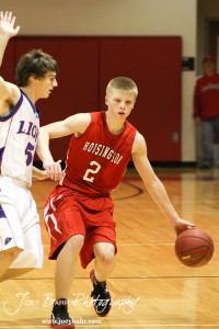 Trent Schremmer (#2) of the Hoisington Cardinals drives towards Minneapolis Lions' defender John Darrow (#5) at the 2012 Hoisington Winter Jam Basketball Tournament.