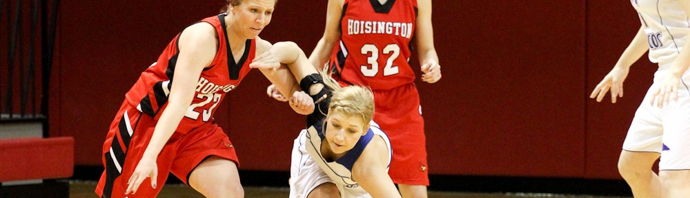 Blakelee Cooper (#23) of the Hoisington Lady Cardinals drives through Russell Lady Broncos defender Madison Beagley (#12) at the 2012 Hoisington Winter Jam Basketball Tournament.