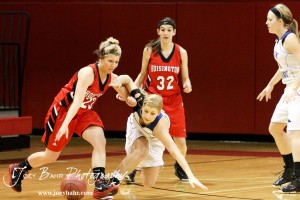 Blakelee Cooper (#23) of the Hoisington Lady Cardinals drives through Russell Lady Broncos defender Madison Beagley (#12) at the 2012 Hoisington Winter Jam Basketball Tournament.