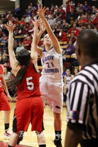 Russell Lady Bronco Kelli Rourke (#21) takes a shot over the defense of Hoisington Lady Cardinal BreAnna Burns (#5) at the 2012 Hoisington Winter Jam Basketball Tournament.