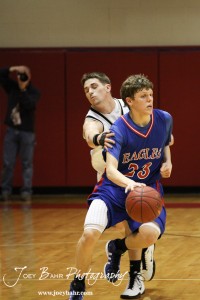 LaCrosse Leopard Tayler Stull (#22) tries to reach around Cody Isern (#23) of the Ellinwood Eagles at the 2012 Hoisington Winter Jam Basketball Tournament.