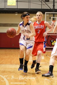 Otis-Bison Lady Cougar Annie Kraisinger (#12) dribbles past Sophie Hayes (#2) of the Ellinwood Lady Eagles at the 2012 Hoisington Winter Jam Basketball Tournament.