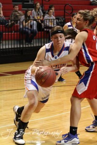 Janel Tammen (#45) of the Otis-Bison Lady Cougars tries to drive past Ellinwood Lady Eagle Lindsey Zink (#24) during the 2012 Hoisington Winter Jam Basketball Tournament.