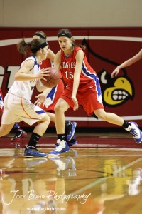 Ellinwood Lady Eagle Rachel Doll (#15) defends against a driving Annie Kraisinger (#12) of the Otis-Bison Lady Cougars at the 2012 Hoisington Winter Jam Basketball Tournament.