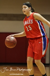 Rachel Doll (#15) of the Ellinwood Lady Eagles looks for a opening in the defense of the Otis-Bison Lady Cougars at the 2012 Hoisington Winter Jam Basketball Tournament.