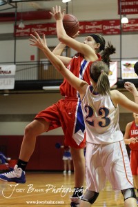 Ellinwood Lady Eagle Rachel Doll (#15) goes up for a shot over Hannah Bannister (#23) of the Otis-Bison Lady Cougars at the 2012 Hoisington Winter Jam Basketball Tournament.