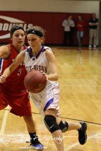Hannah Bannister (#23) of the Otis-Bison Lady Cougars drives past Jenna Snell (#5) of the Ellinwood Lady Eagles at the 2012 Hoisington Winter Jam Basketball Tournament.
