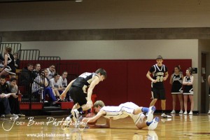 Justus Bartonek (#1) of the Otis-Bison Cougars dives for a ball dropped by LaCrosse Leopard Clayton Basgall (#12) at the 2012 Hoisington Winter Jam Basketball Tournament.