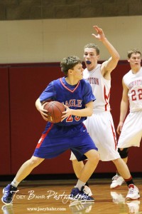 Ellinwood Eagle Cody Isern (#23) looks to make a pass against the defense of Hoisington Cardinal Jacob Durrett (#3) at the Hoisington Activities Center in Hoisington, Kansas on February 10, 2012.  Photo: Joey Bahr