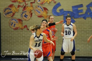St. John Lady Tiger Tara Christie (#15) dribbles against Otis-Bison Lady Cougar Annie Kraisinger (#12) while Otis-Bison Lady Cougar Kim Pechanec (#32) and St. John Lady Tiger Teresa Christie (#20) look on at St. John High School in St. John, Kansas on February 21, 2012.  Photo: Joey Bahr
