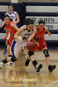 St. John Lady Tiger Teresa Christie (#20) and Otis-Bison Lady Cougar Hannah Bannister (#23) battle for the basketball at St. John High School in St. John, Kansas on February 21, 2012.  Photo: Joey Bahr