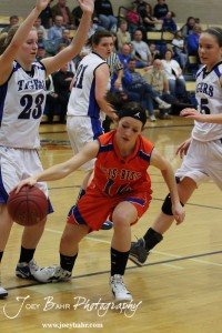 Otis-Bison Lady Cougar Annie Kraisinger (#12) drives against the defense of Alexis Witt (#23) of the St. John Lady Tigers at St. John High School in St. John, Kansas on February 21, 2012.  Photo: Joey Bahr